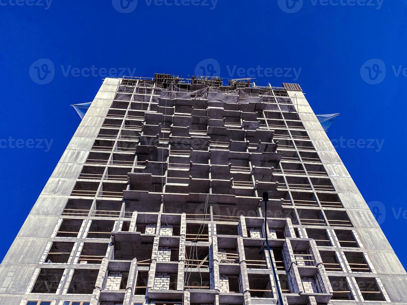 Large tall building unfinished concrete panel and monolithic frame new buildings against the blue sky at a construction site photo