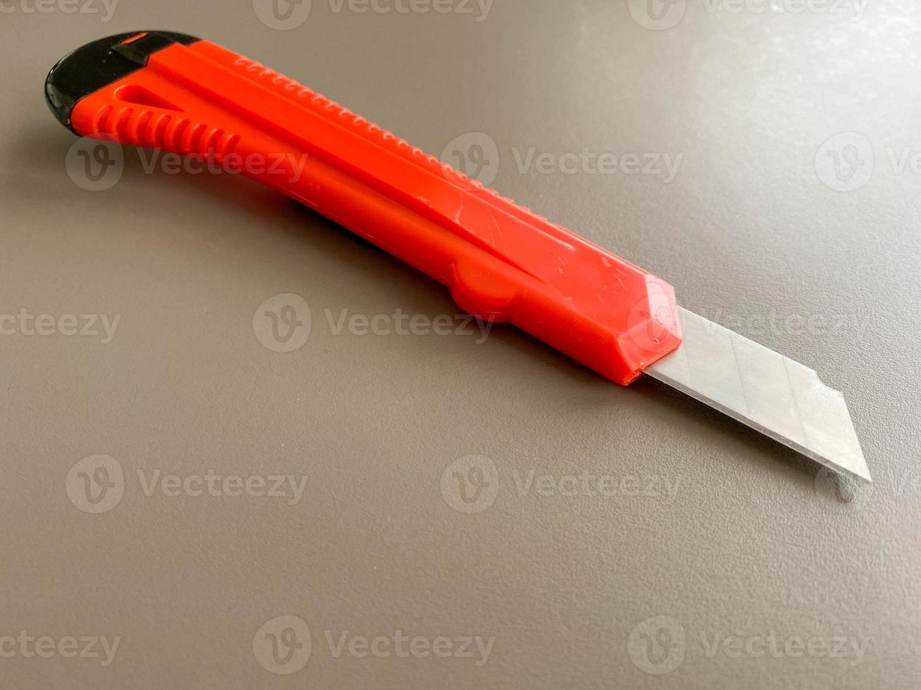 Red sharp office stationery knife with a paper cutting blade on a desktop office desk. Business work photo