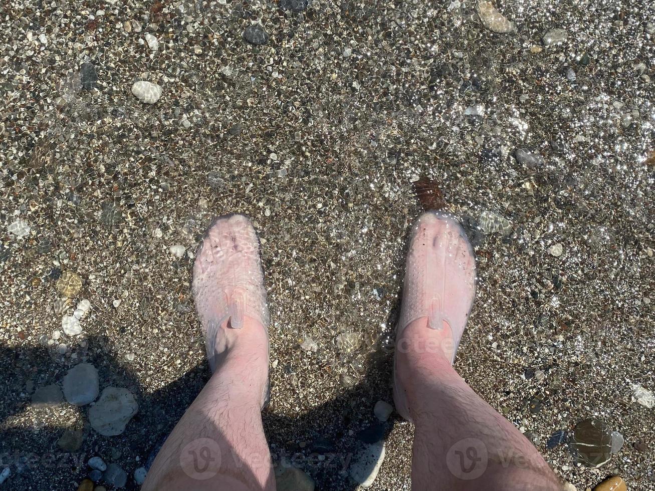 Low Section Of Man Standing On Beach photo