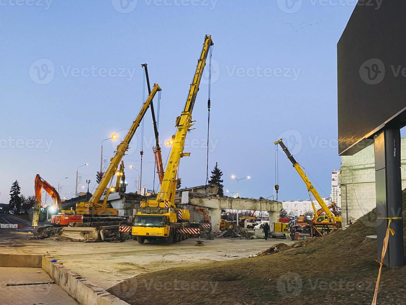 construction of a broken bridge on a busy road. huge, yellow, metal cranes carry concrete blocks and beams for the construction of an overpass photo