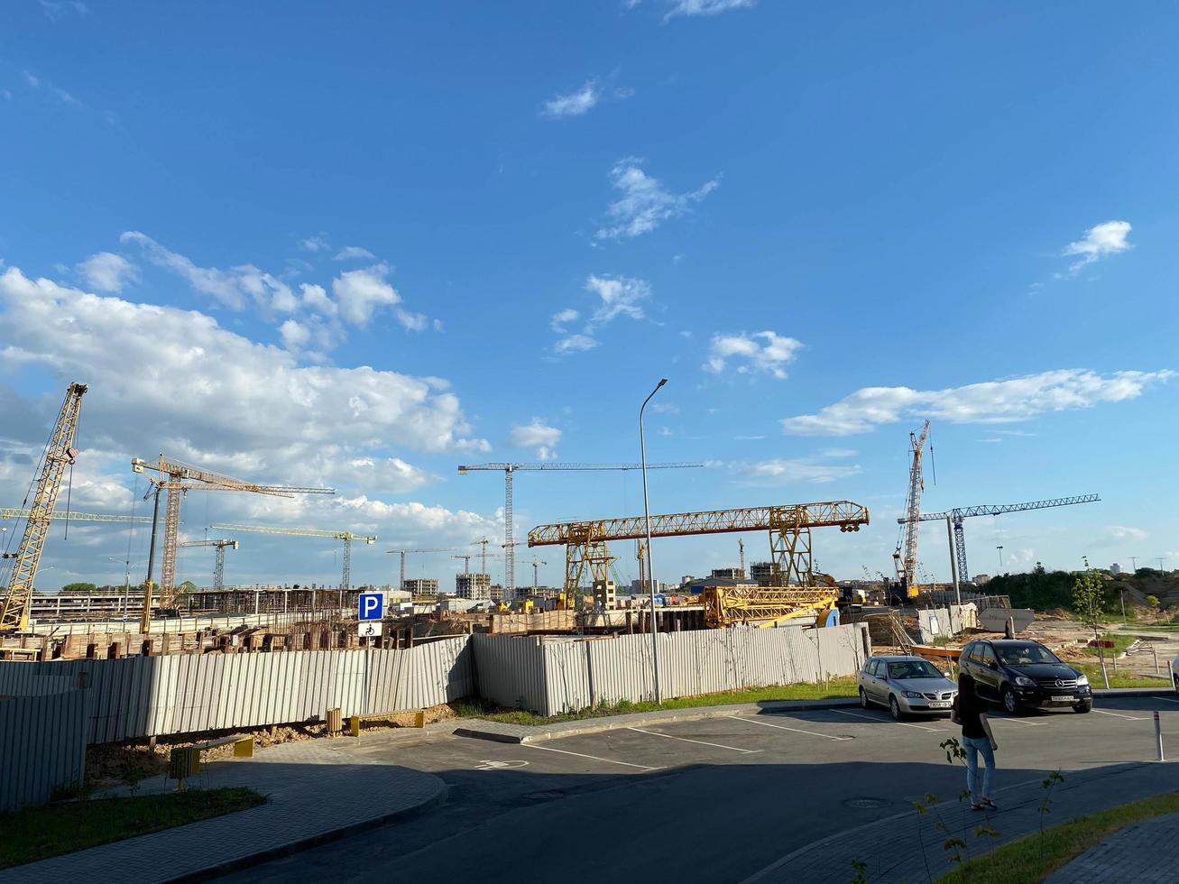 edificio en construcción con encofrado de hormigón, andamios, puntales, redes de seguridad, trabajadores y con una grúa de acero amarillo sobre un fondo de cielo azul con rastros de nubes foto