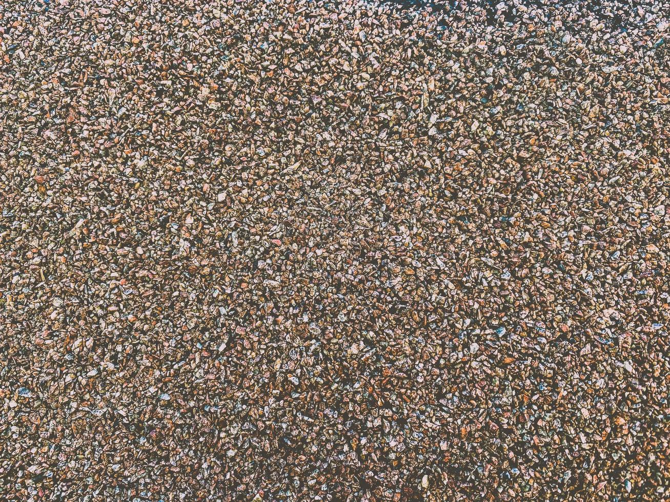 The texture of a gouged rough stone surface with small sharp stones of different colors. The background photo