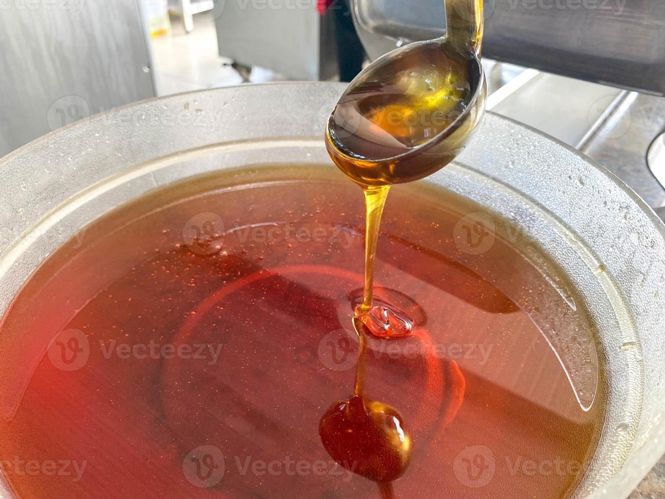 Tasty natural yellow golden bee honey flows in a thin stream from a spoon into a plate photo