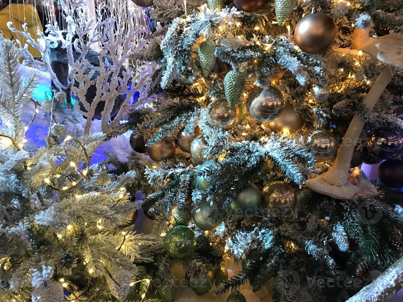 adornos navideños en el árbol de vacaciones. muchas bolas de colores, guirnaldas, lámparas brillantes y bayas rojas en las ramas están salpicadas de nieve. fondo transparente tradicional festivo para el nuevo año foto