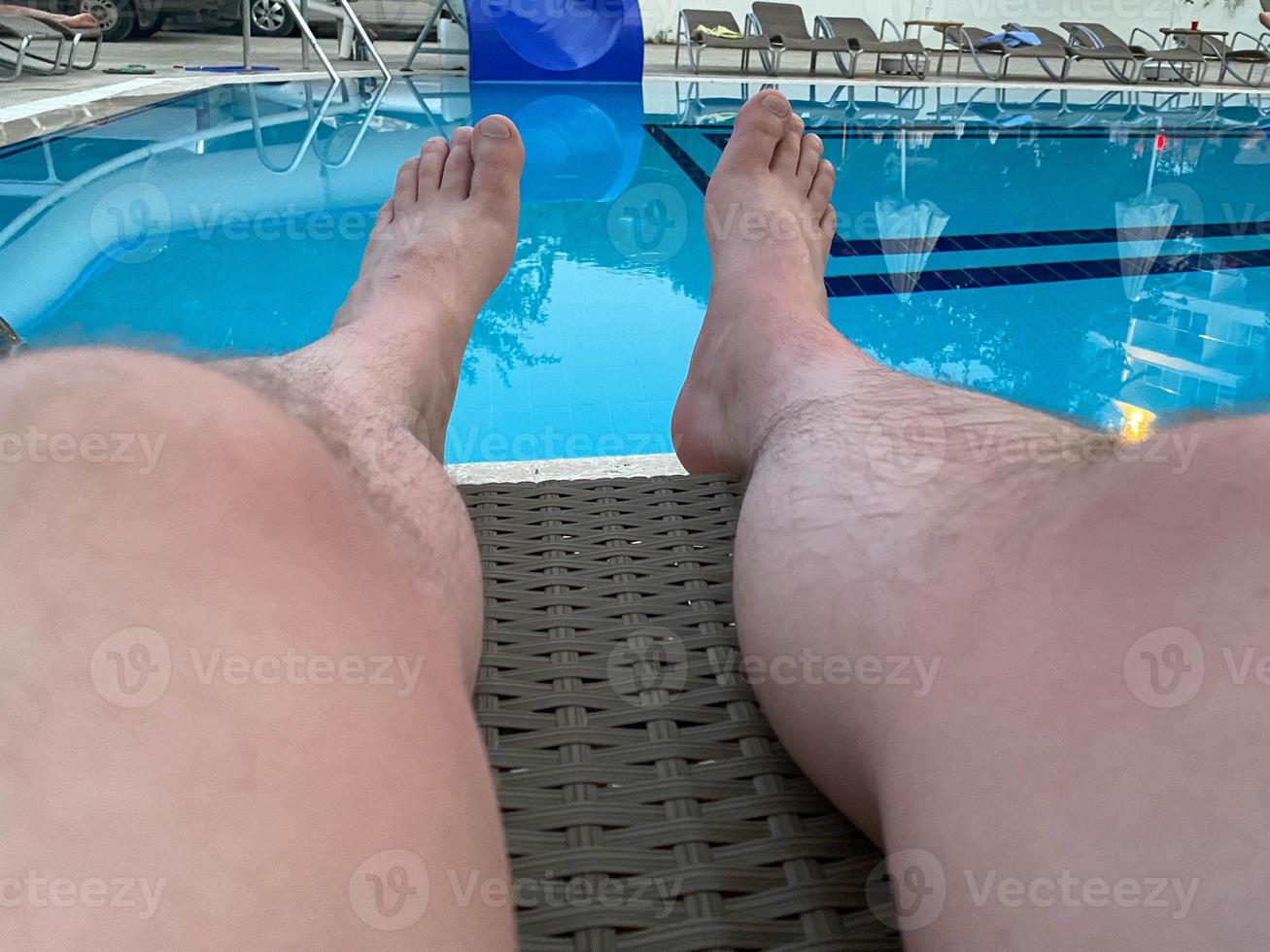 estancia en el complejo. piernas de los hombres sobre un fondo de agua grande. hombre nadando en la piscina. El concepto de recreación, relajación, turismo. foto