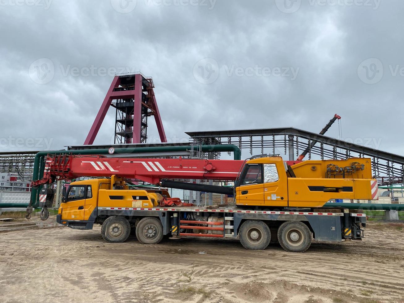Large crane is hoisting cargo from the long trailer to the factory floor photo