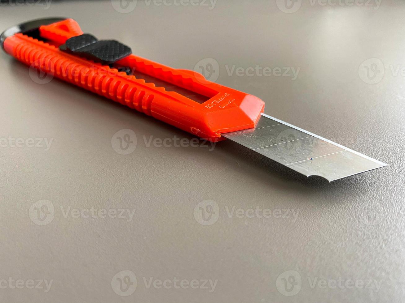 Red sharp office stationery knife with a paper cutting blade on a desktop office desk. Business work photo