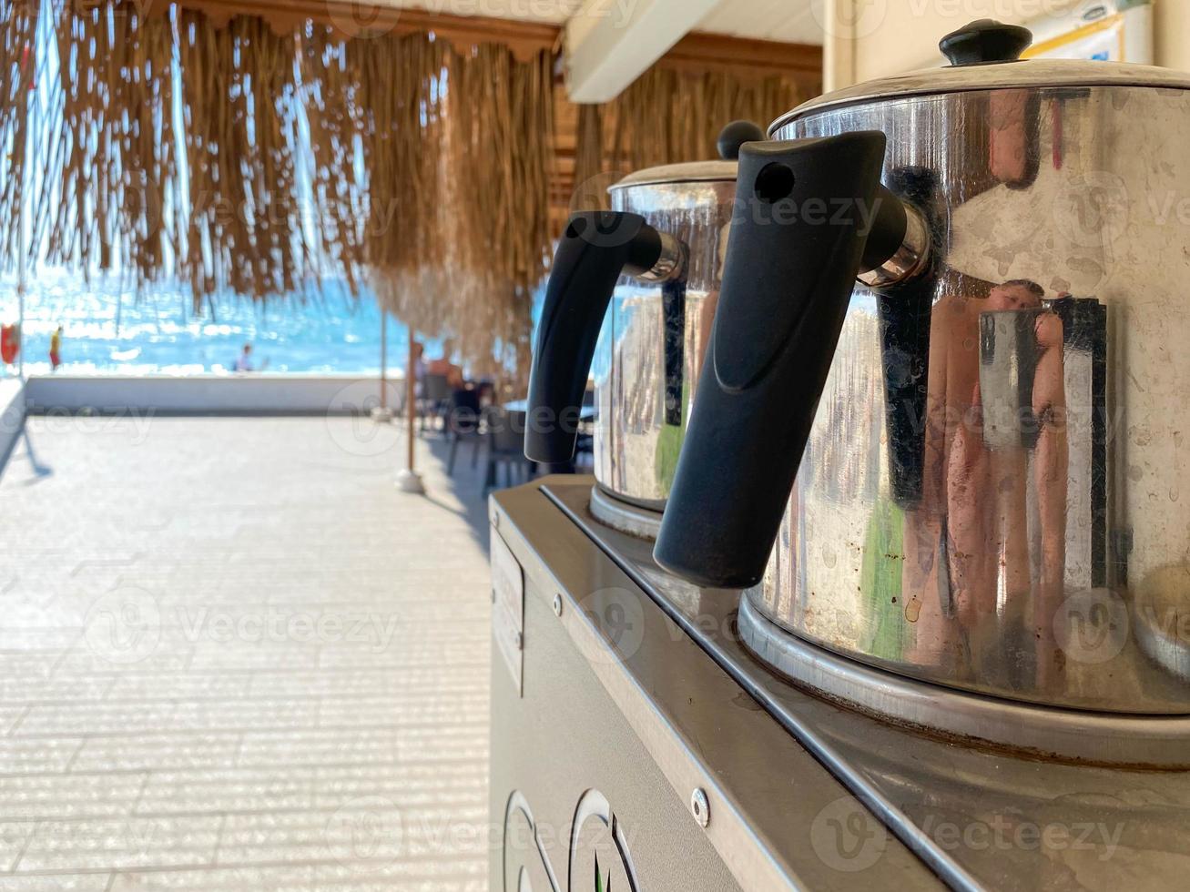 Two metal chrome-plated electric kettles for boiling water for tea stand outside in the open air photo