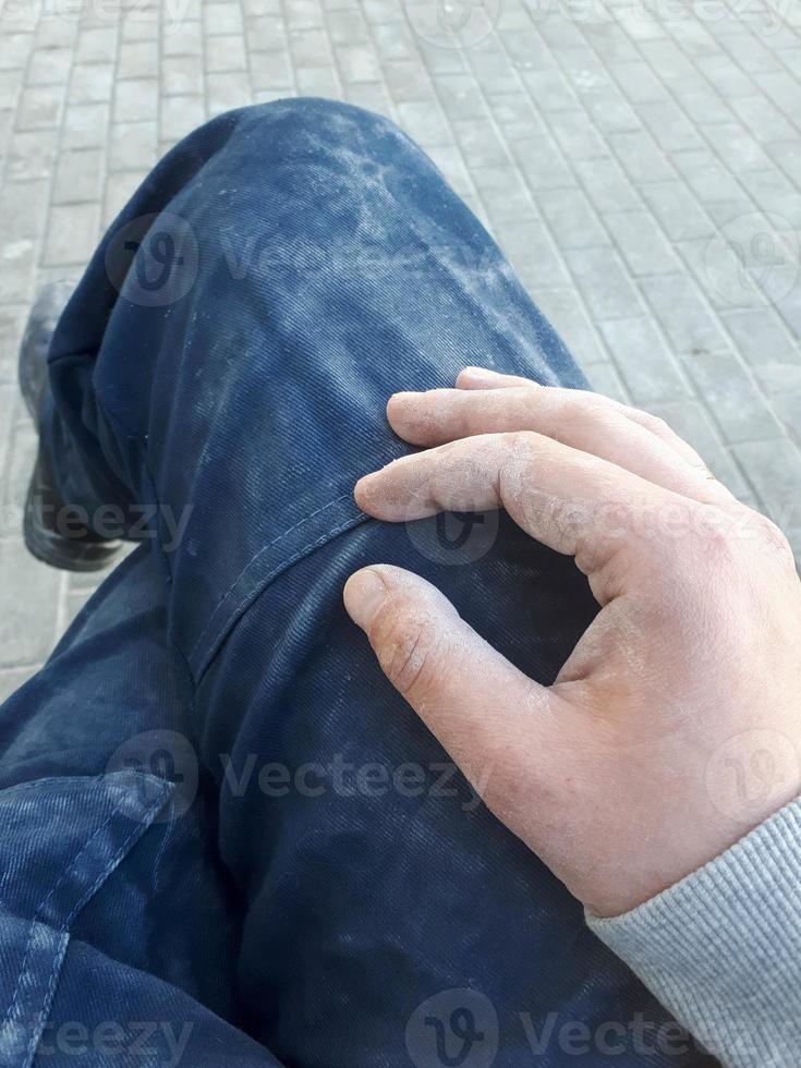 Dirty dusty legs of a male worker in whitewashed pants and an arm. Dirty physical work photo