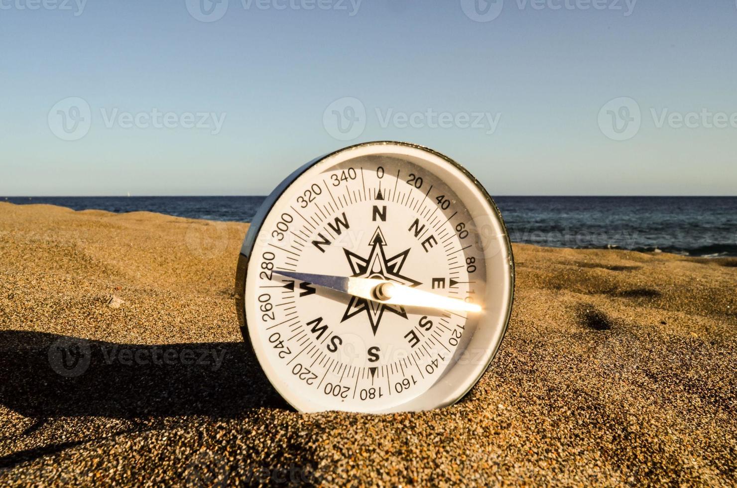 Compass on the ground by the ocean photo
