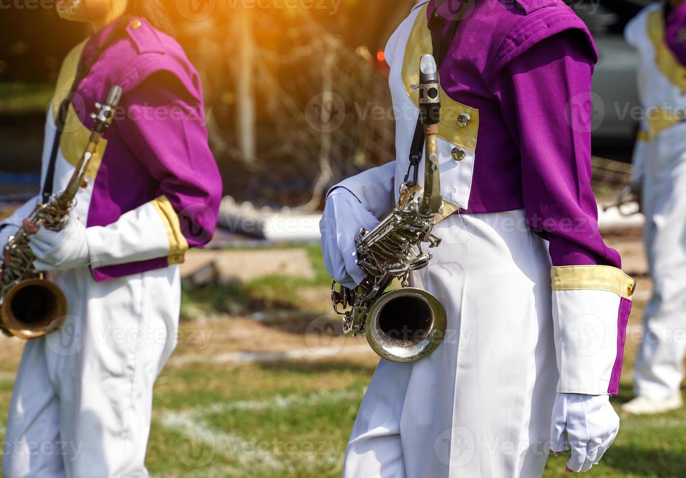 A saxophone is held in the hands of the school orchestra students who play at the school sports competition. Soft and selective focus. photo