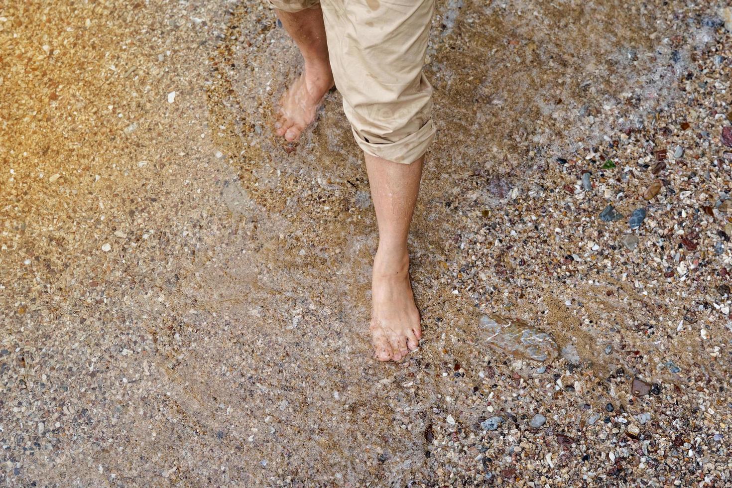 una mujer asiática dobla las piernas de sus pantalones para evitar que se mojen mientras camina por la playa. enfoque suave y selectivo. foto