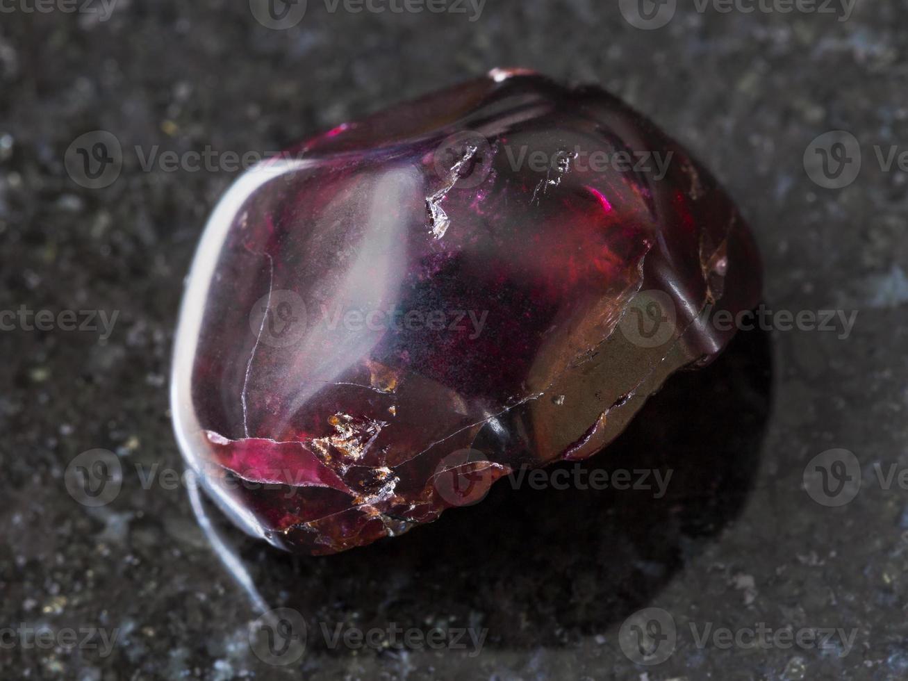 tumbled red garnet gemstone on dark background photo