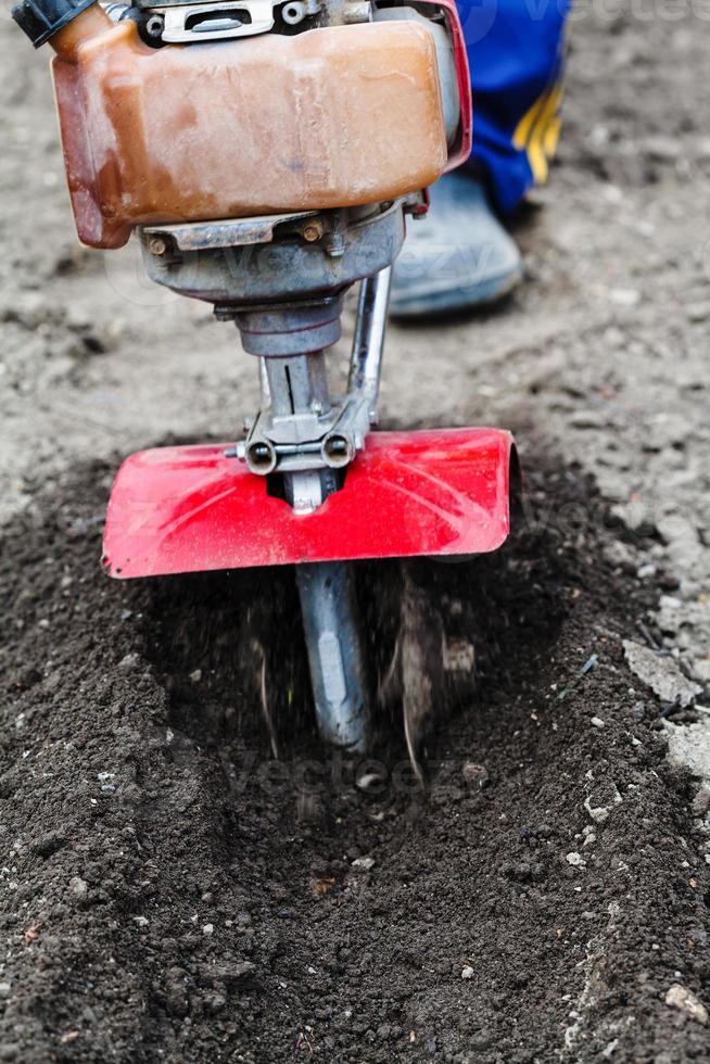 farmer plows field by tiller in spring photo