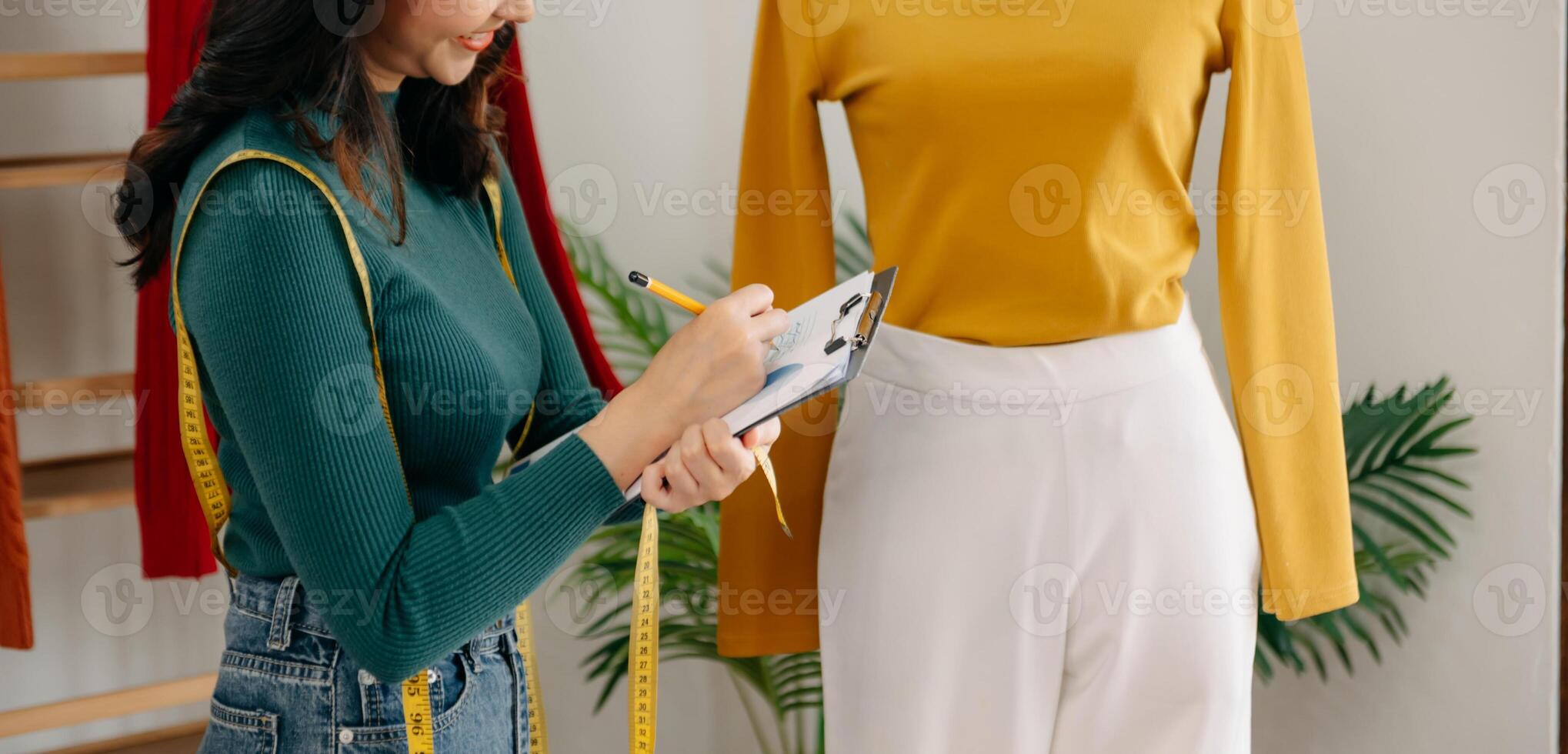 The designer is measuring the shirt fashion working on her designs in the studio. photo
