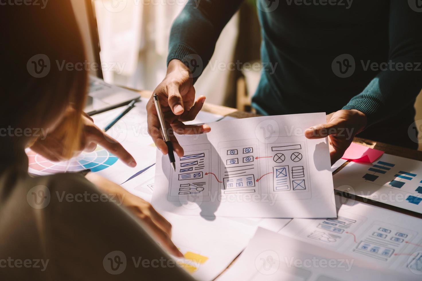UX developer and ui designer brainstorming about mobile app interface wireframe design with customer breif and color code at modern office. photo