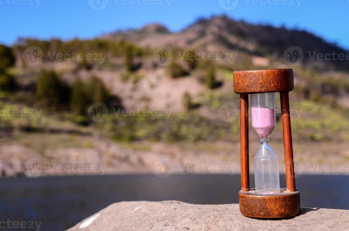 Wooden hourglass by the river photo