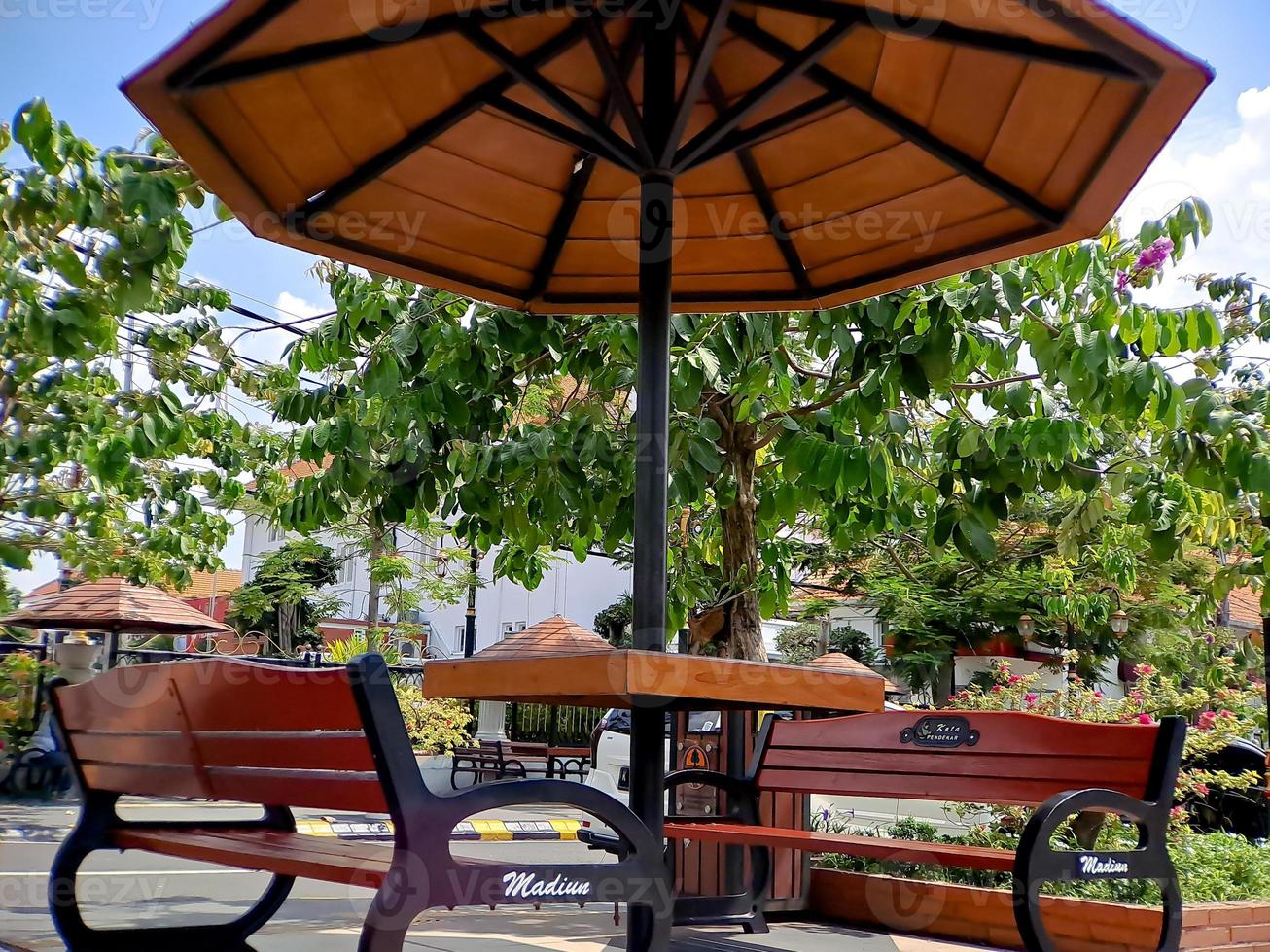 resting place benches and umbrellas made of black brown wood and iron, bright blue sky in the garden of the city of Madiun Indonesia. photo