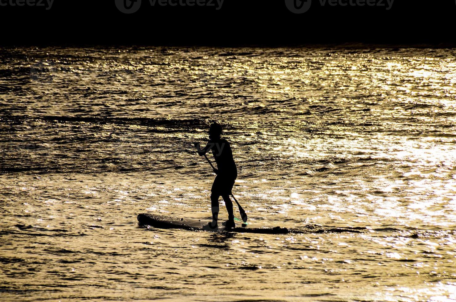 Silhouette of a man in paddle board photo