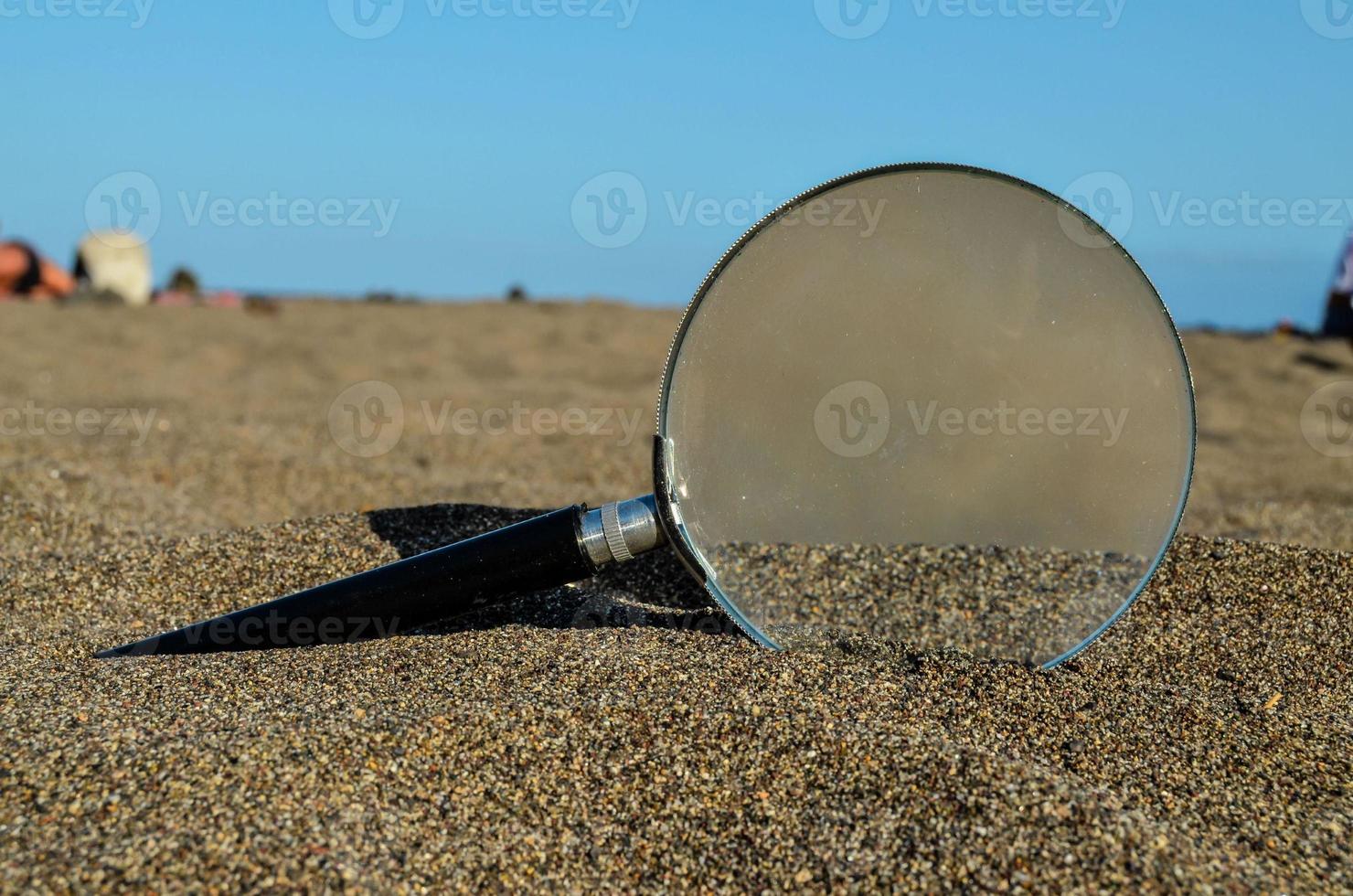 Magnifying glass in sand photo