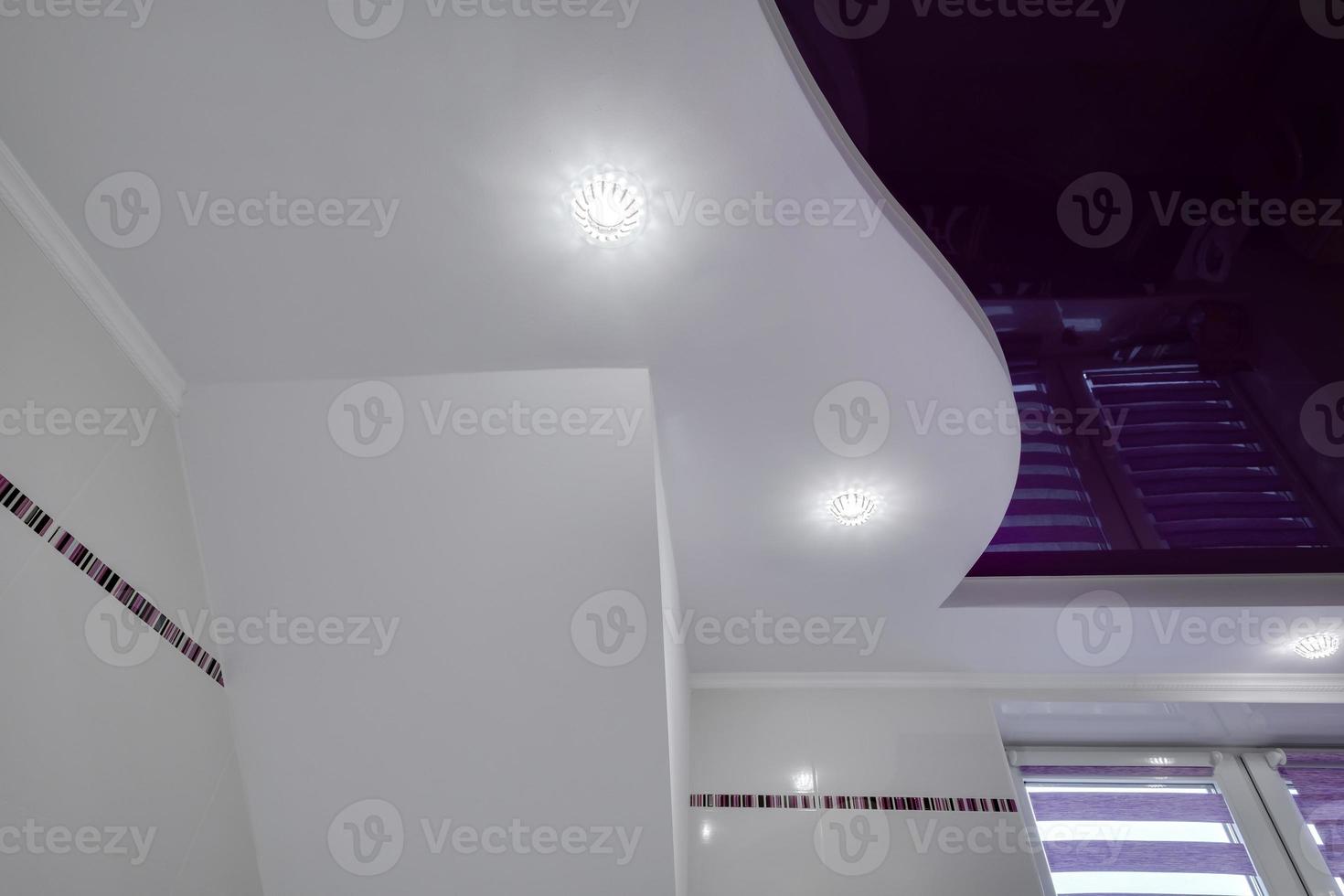 Detail of corner ceiling with intricate stucco work. Suspended ceiling and drywall with halogen spots lamps in room in apartment or house. Stretch purple ceiling of complex shape. photo