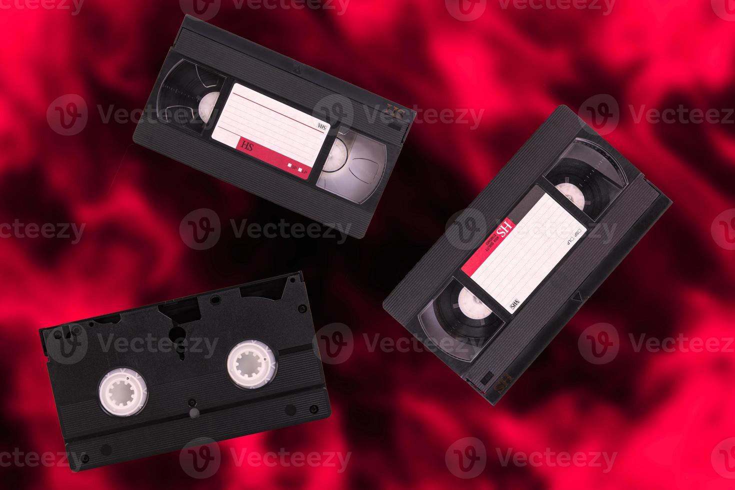 Three video cassettes, VHS, Pal Secam, red and black blurred retro background. photo