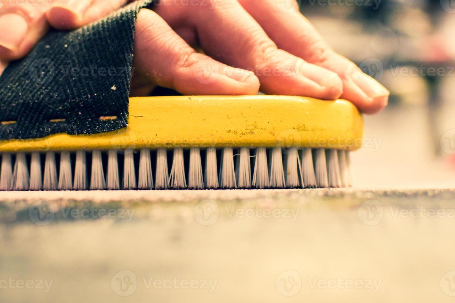 Hand hold brush and brushing wax on snowboard close up. Snowboard preparation in ski repair shop photo