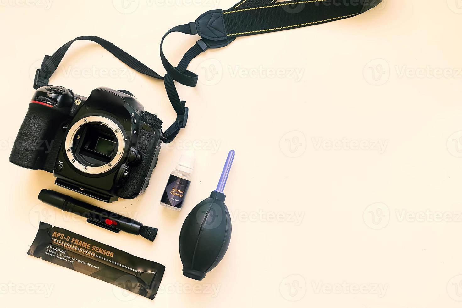 Top view close up camera sensor and lens cleaning tools with dslr camera on white background. Selective focus. Brush, blower, camera, swab, liquid tube, work space photo