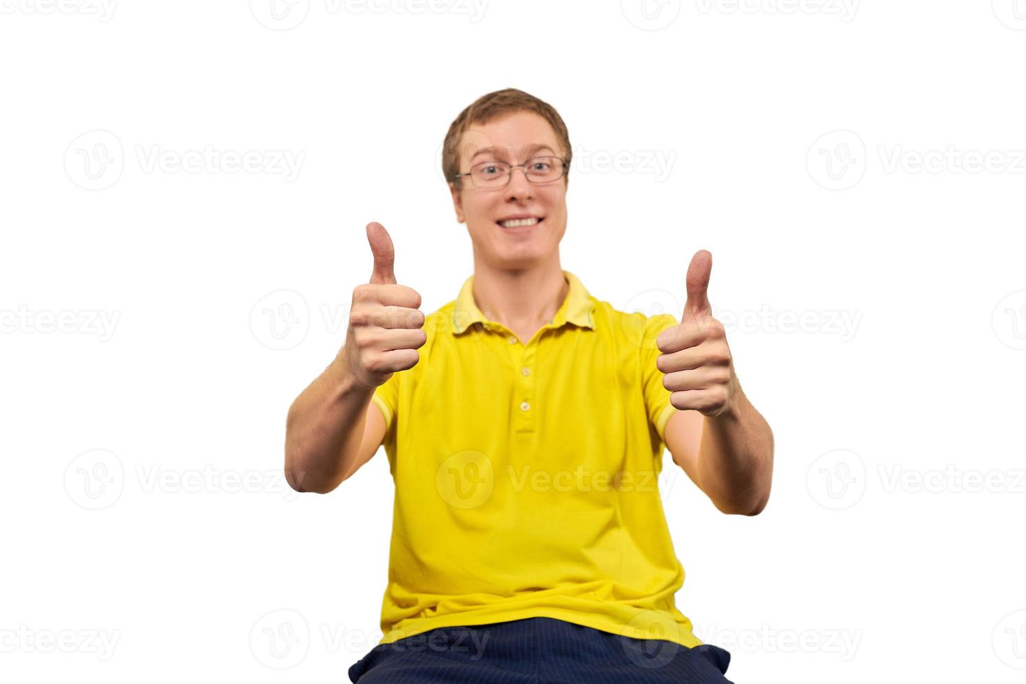 Funny young man in glasses and yellow T-shirt showing thumbs up gesture isolated on white background photo