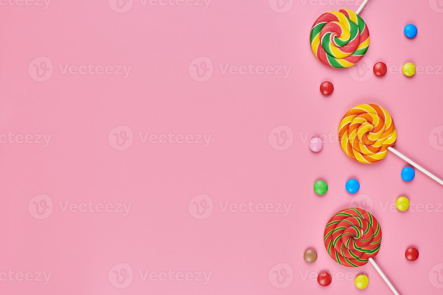 Sweet lollipops and candy on pink background photo