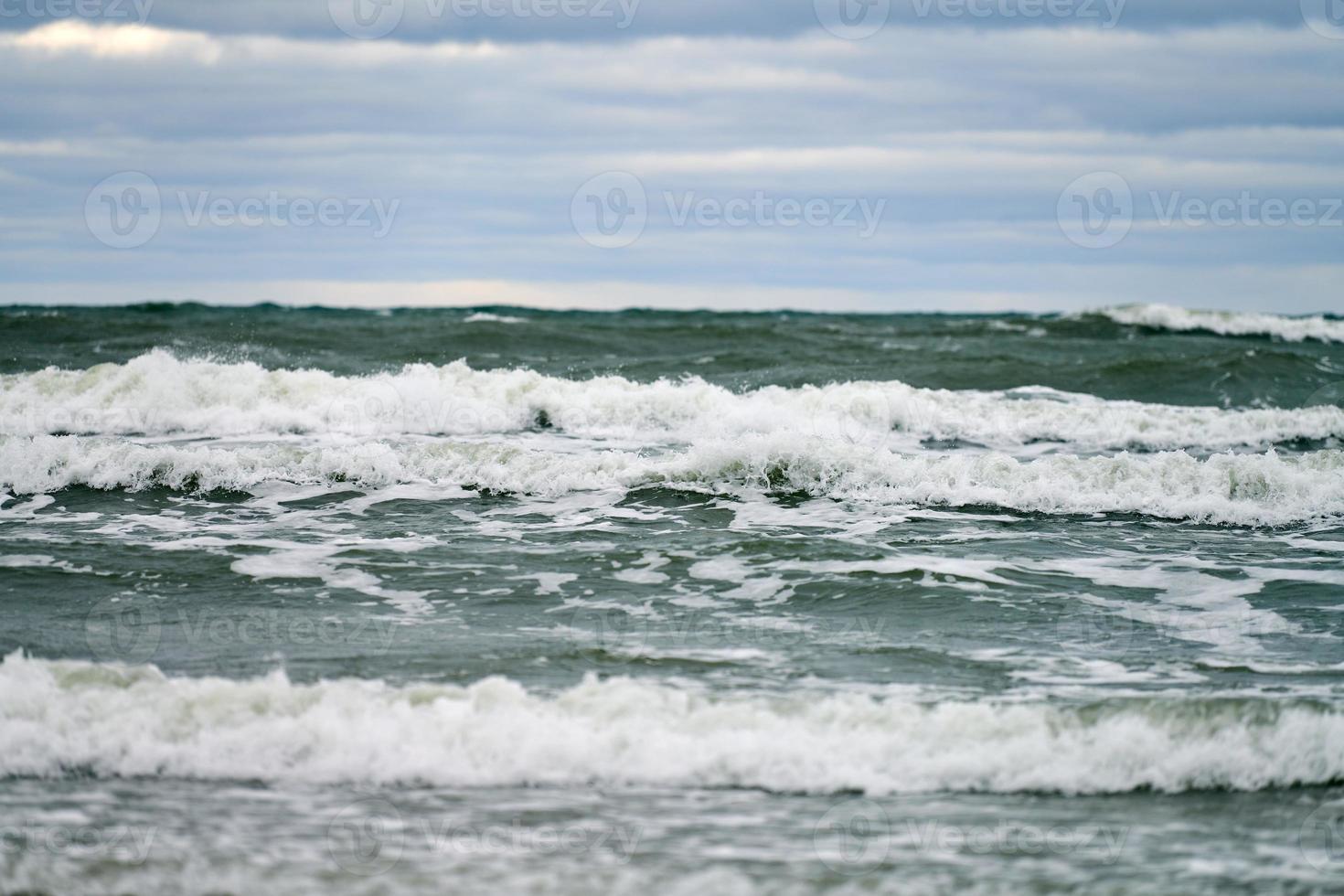 Blue sea with foaming waves and cloudy sky, seascape photo