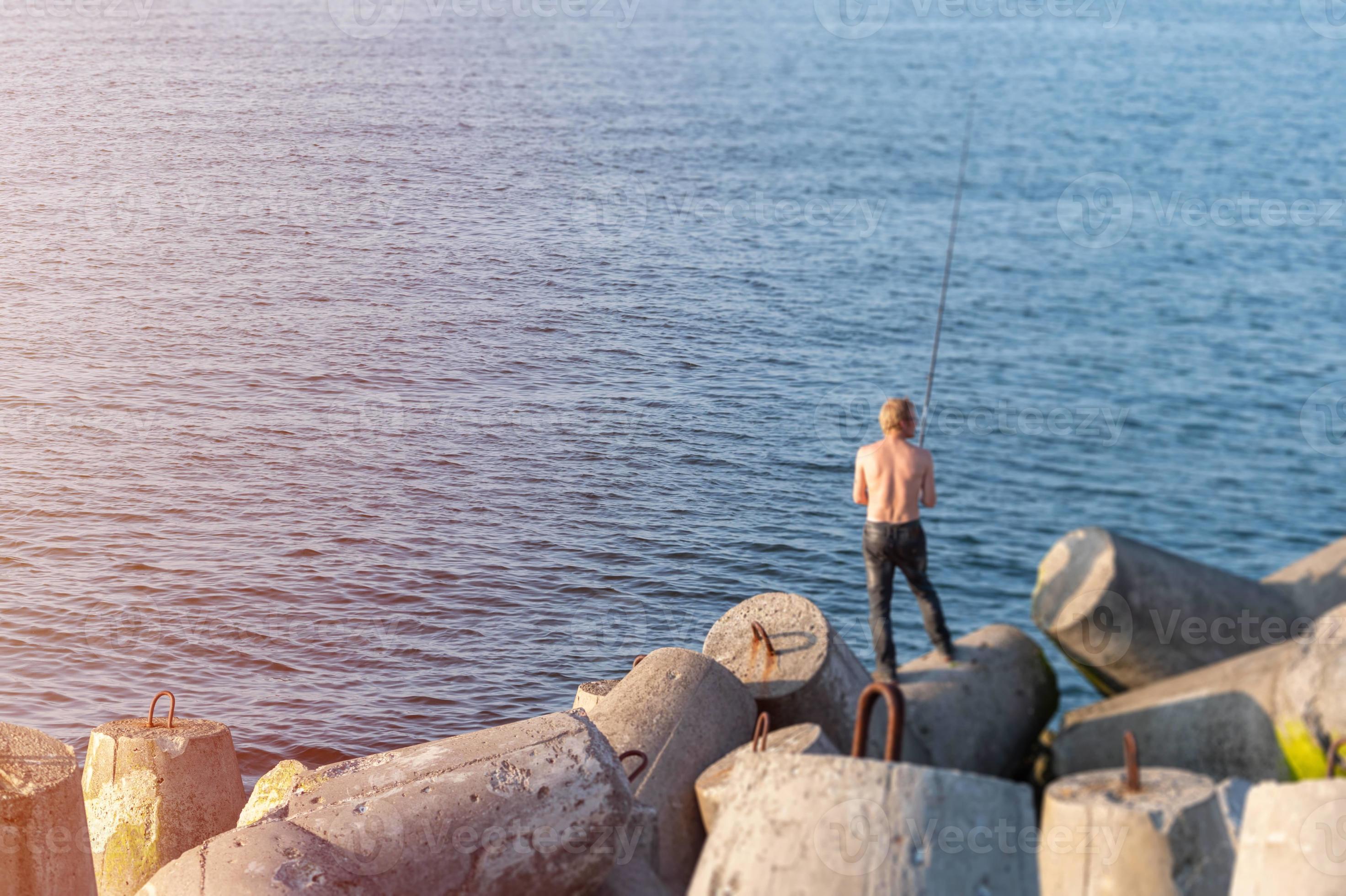 Fisherman fishing from breakwaters, copy space. Bare back pescetarian man  with fishing rod. Rich catch, fish place. 14790485 Stock Photo at Vecteezy