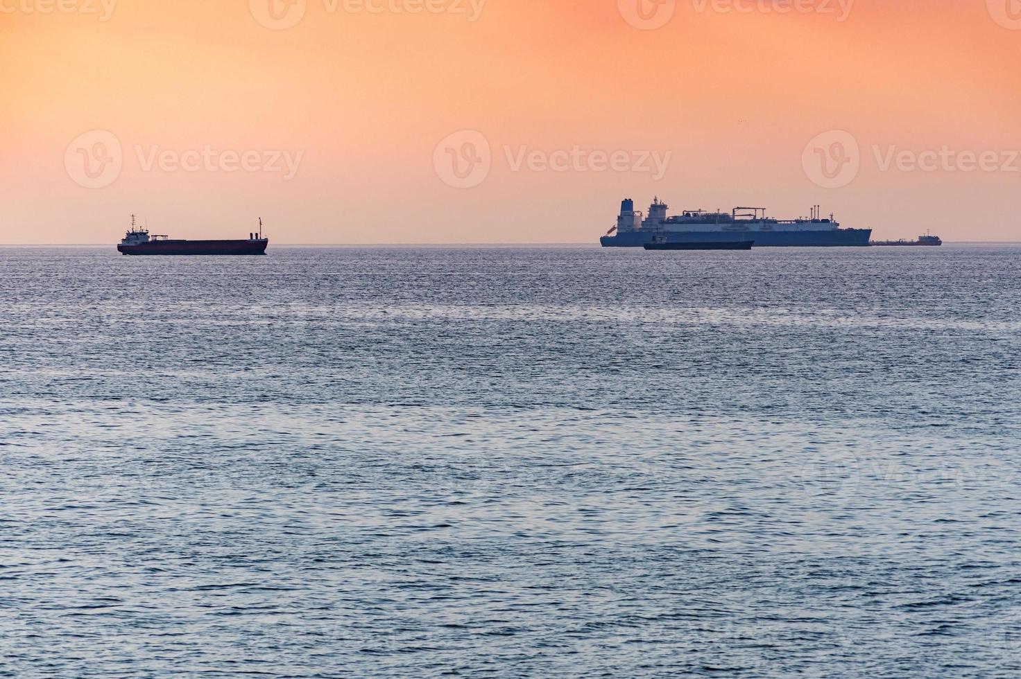 Cargo ships and barge at beautiful sunset. Amazing evening seascape, breathtaking travel view, copy space. Anchorage for ships photo