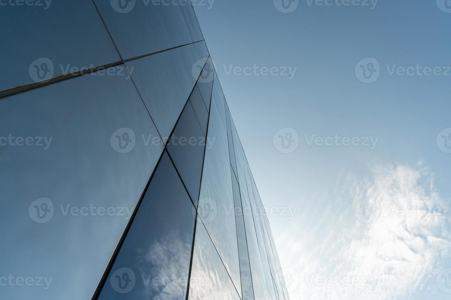 Modern mirror wall decoration of business center, copy space. Bottom view to texture of exterior design. Contemporary pattern of buildings. Looking up. photo
