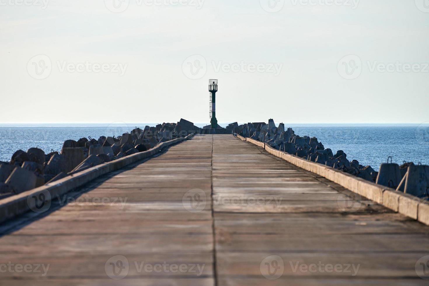 muelle de hormigón largo vacío con rompeolas y faro de señales en el puerto europeo, espacio de copia foto