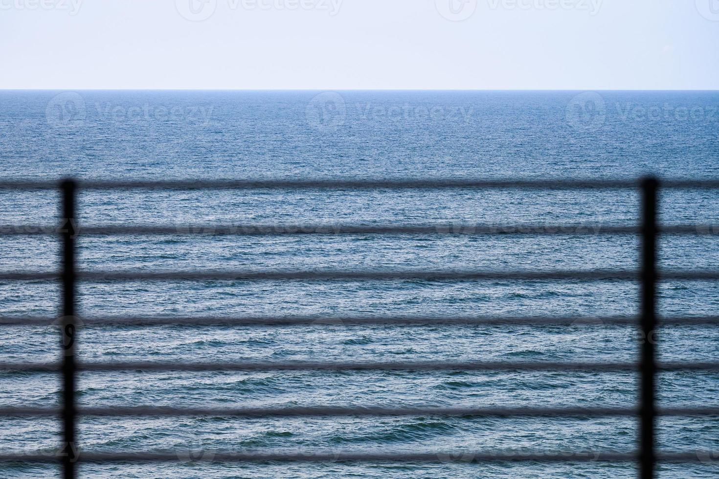 Fencing on observation deck, blue sea background, protection of tourists from falling off cliff photo