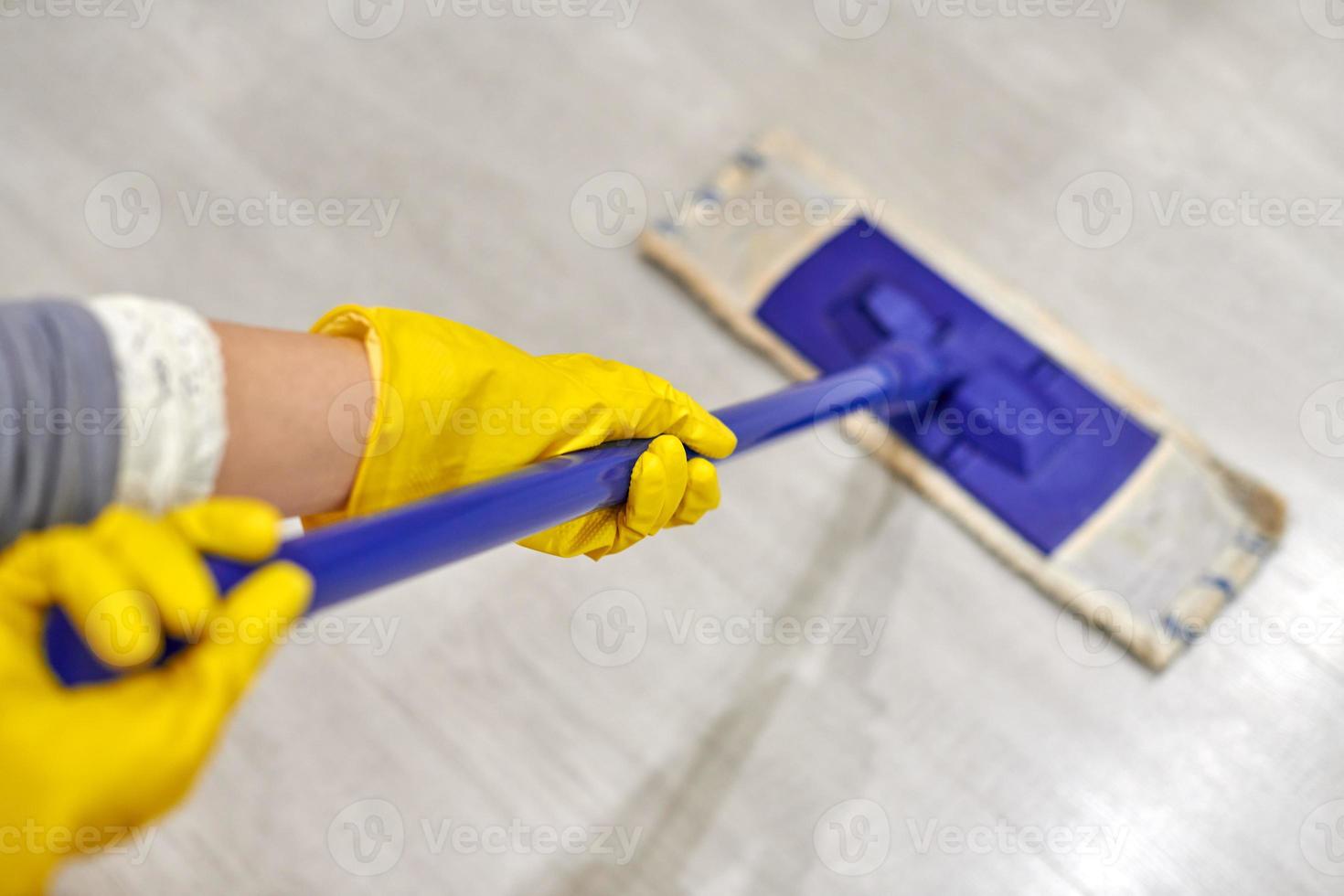 Girl in protective gloves cleaning floor using flat wet mop. photo
