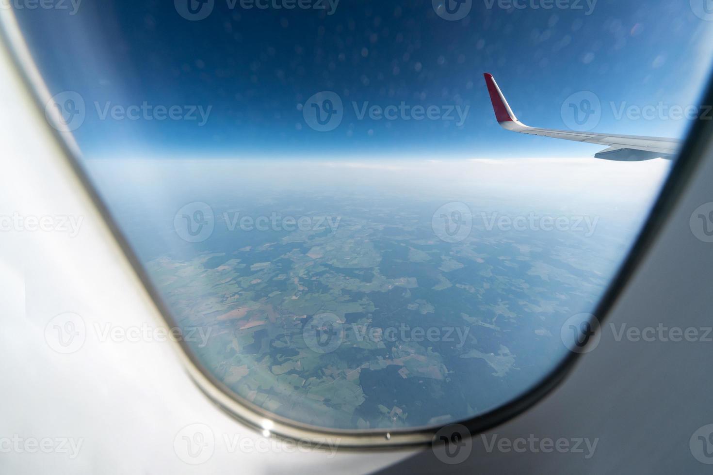 vista de la ventana del avión al cielo nublado y la tierra. hermoso paisaje desde la cabina del avión. volar sin miedo a volar, incidentes y turbulencias. foto