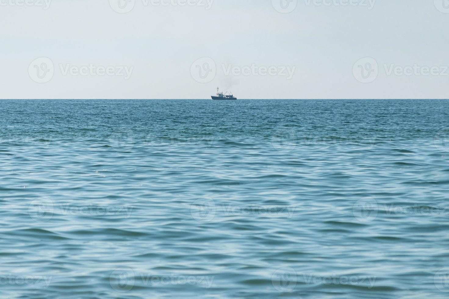 Fishing ship at sea. Lonely boat trawler goes to port for sell fish catch. Calm clear sunny weather. Beautiful horizon of seascape. photo