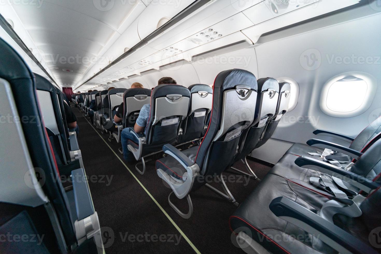 Airplane cabin seats with passengers. Economy class of new cheapest low-cost airlines. Travel trip to another country. Turbulence in flight. photo