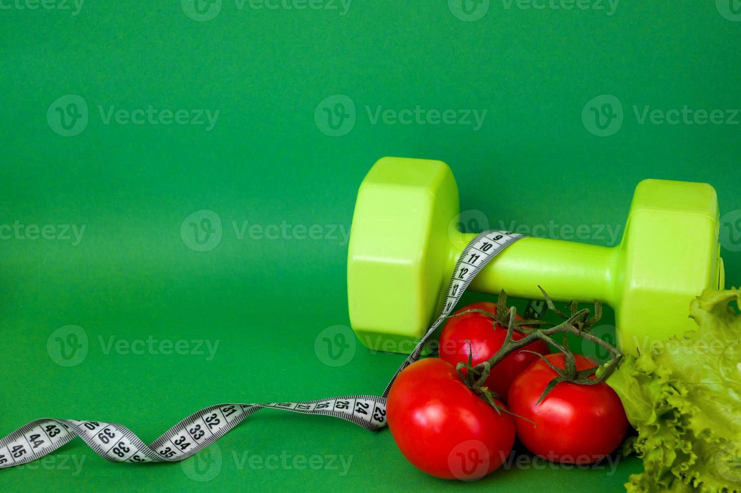 Side view of dumbbell against green background near measring tape. Workouts and sport concept. Healthy lifestyle.Vegetables photo