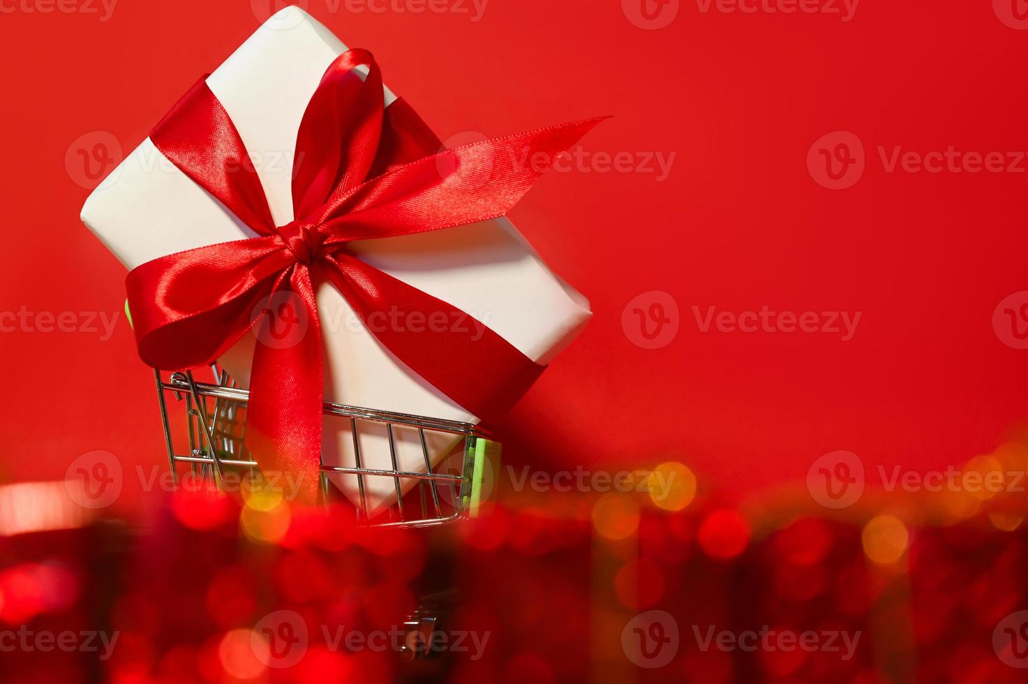A big gift box in a cart against red background. Holidays shopping and sale. Discounts. Mockup photo