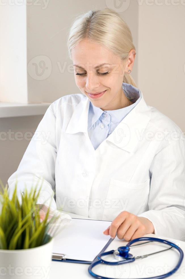 Vertical banner with happy young doctor filling out paperwork and writing out prescriptions photo