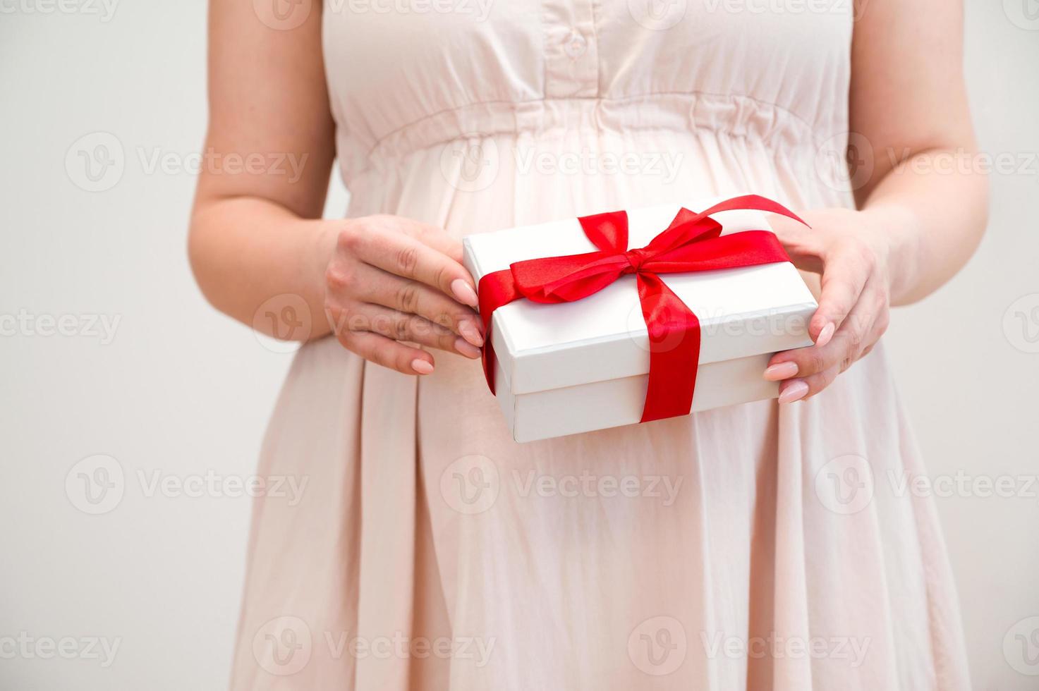 Mother's day or baby shower concept. Pregnant woman holding present photo