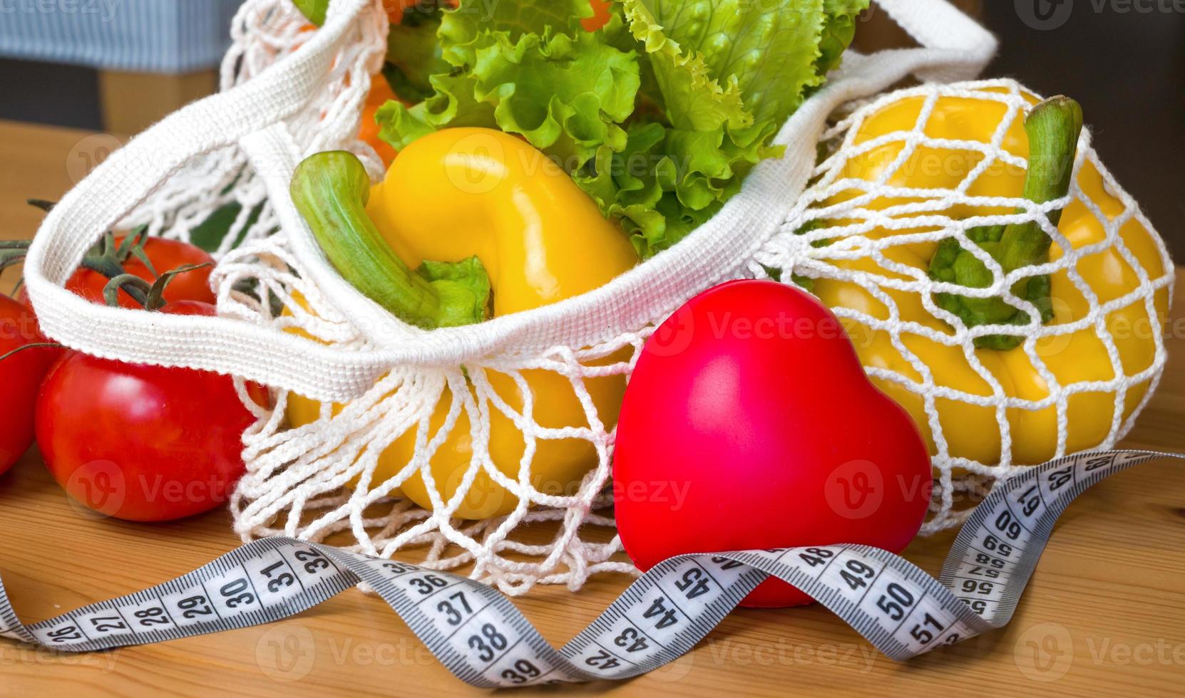 concepto de dieta saludable. verduras en una bolsa de hilo cerca de la cinta métrica. vegetariano, vegano. foto