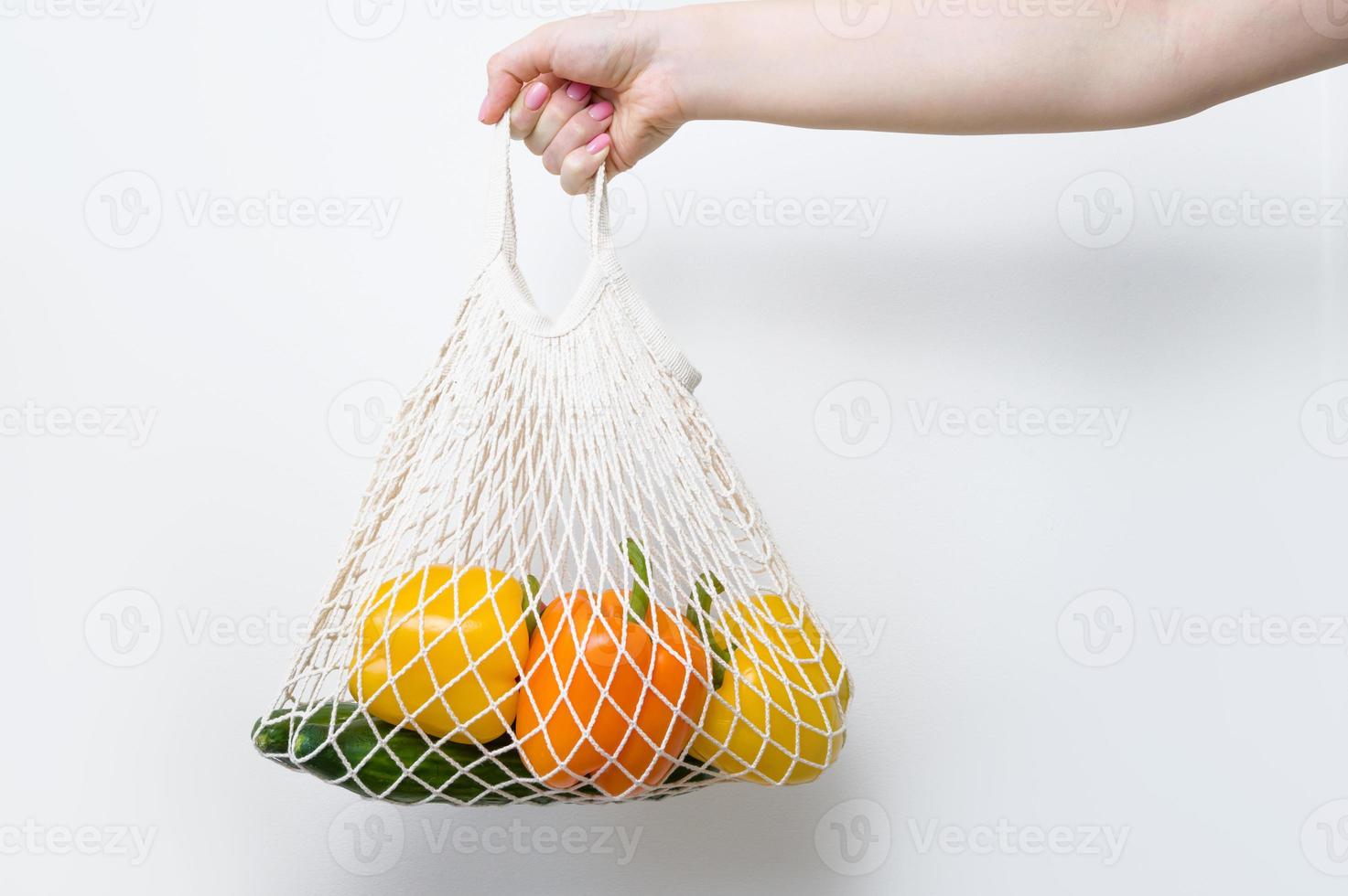 primer plano de la mano de una mujer sosteniendo un comprador ecológico con verduras frescas. concepto de compra sostenible. alimentación saludable foto