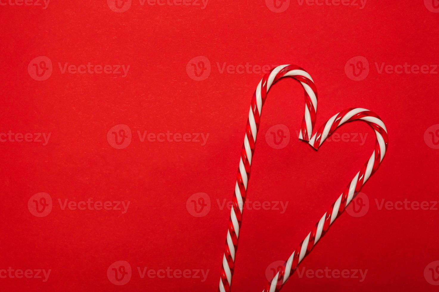 Two candy canes making a heart on a red textured background. Minimalistic christmas banner.Copyspace photo