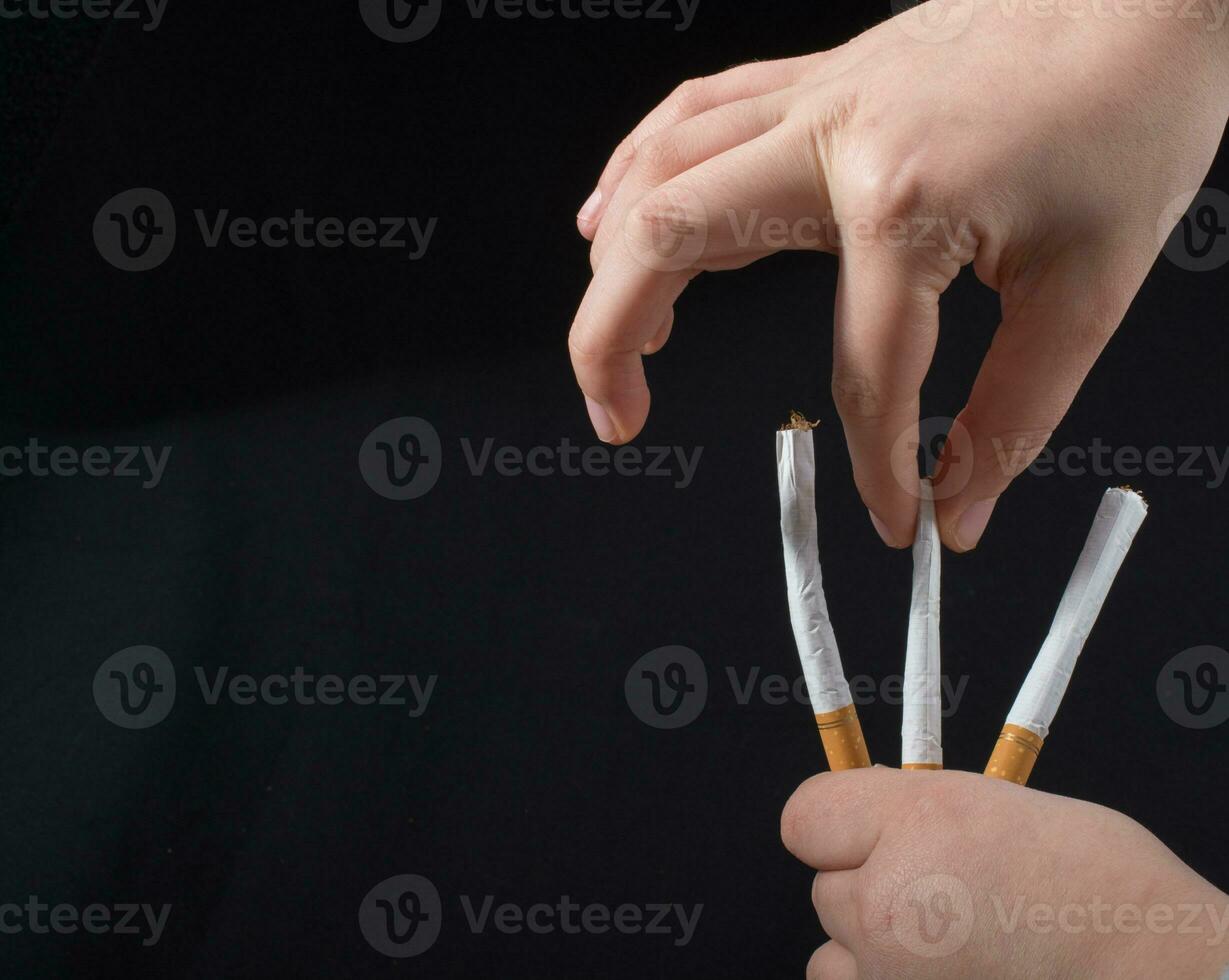 Hand is holding  cigarettes on black background photo