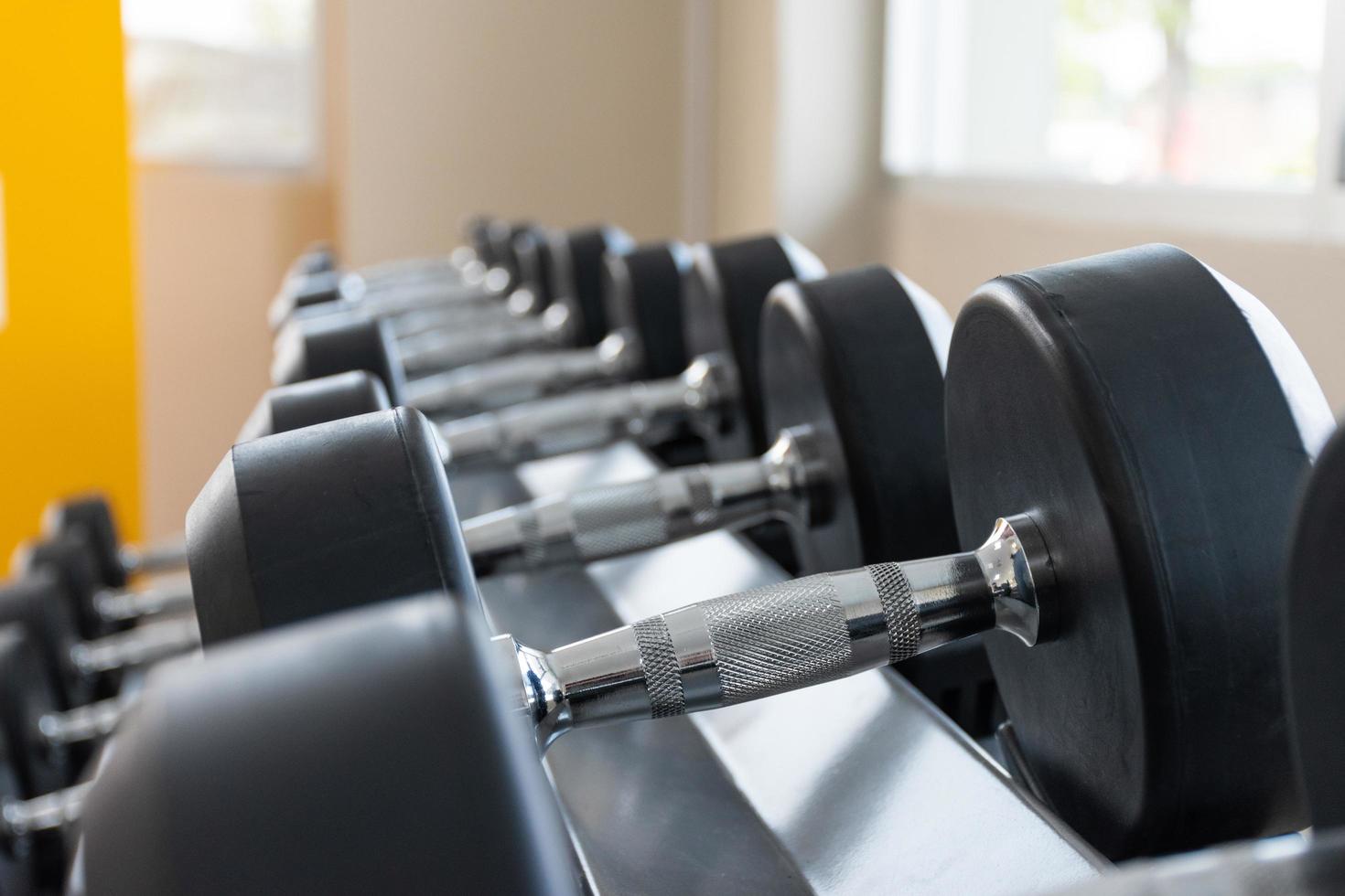 Black dumbbell set on rack close up in sport fitness center weight training equipment concept photo