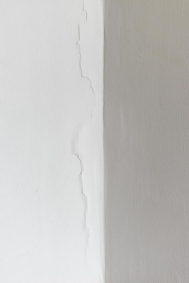 la pared de hormigón blanco de textura tiene grietas. foto